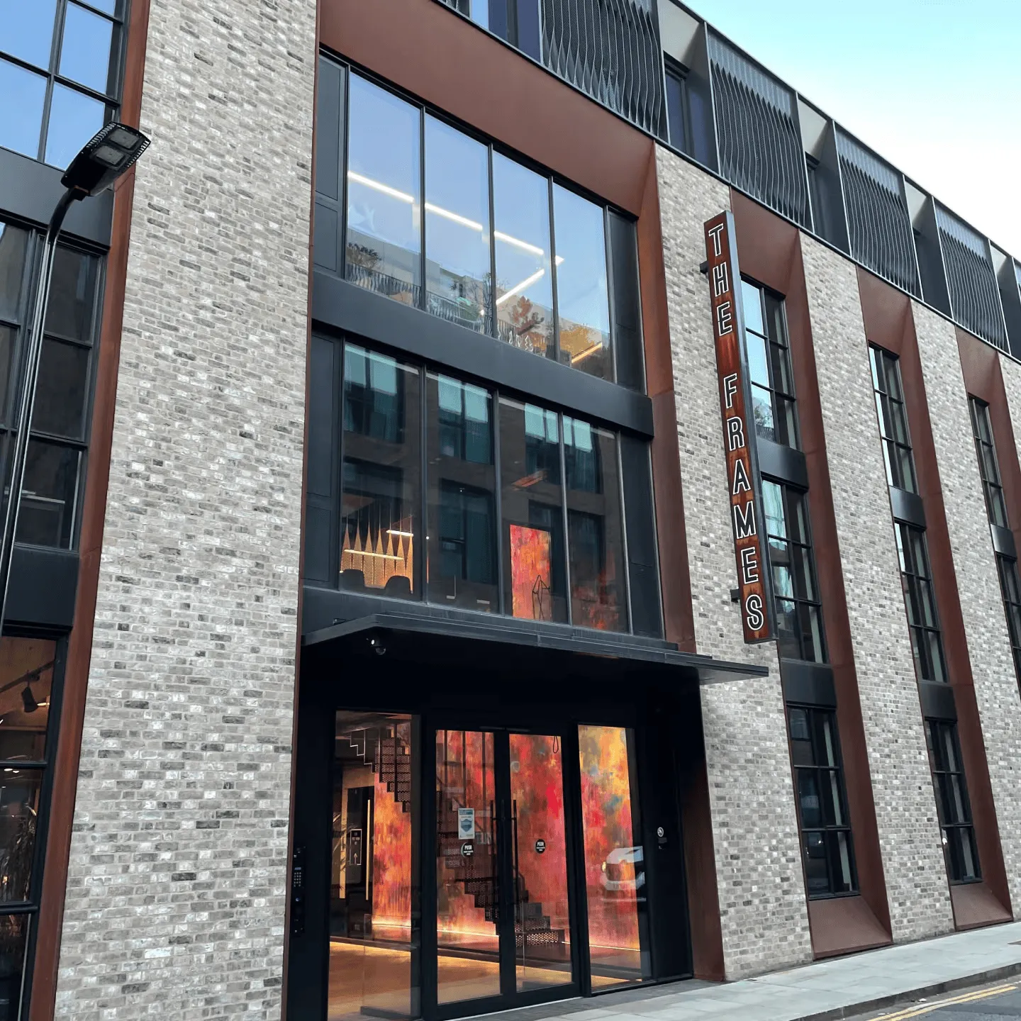 Exterior of The Frames modern brick and glass building with vertical signage above the entrance