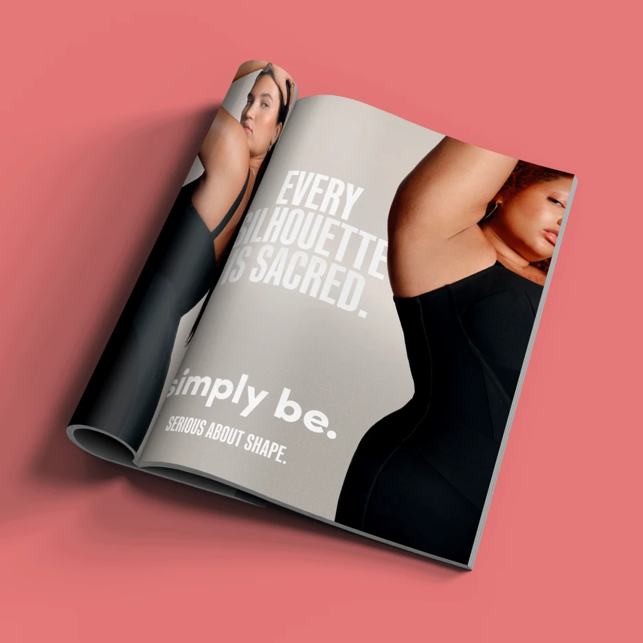 Open fashion magazine featuring inclusive body-positive advertising campaign with bold typography and studio photography