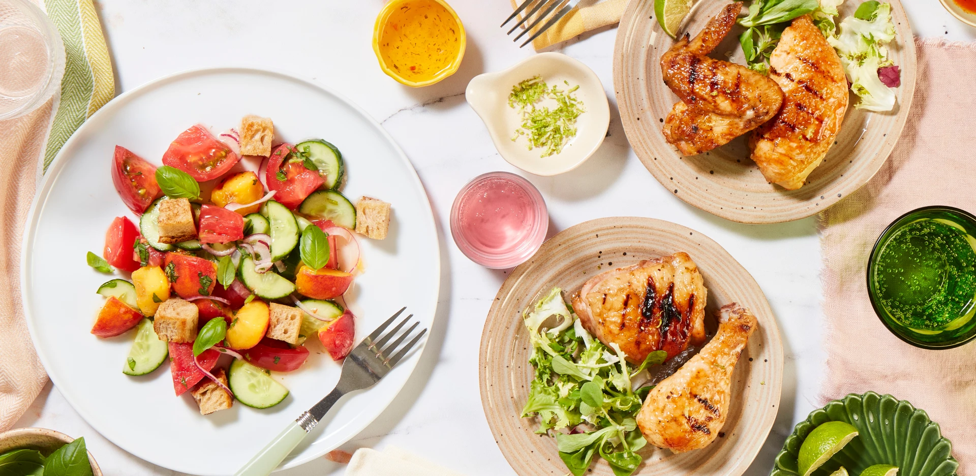 Food styling setup with grilled chicken, fresh salad, drinks and condiments arranged on plates for photography